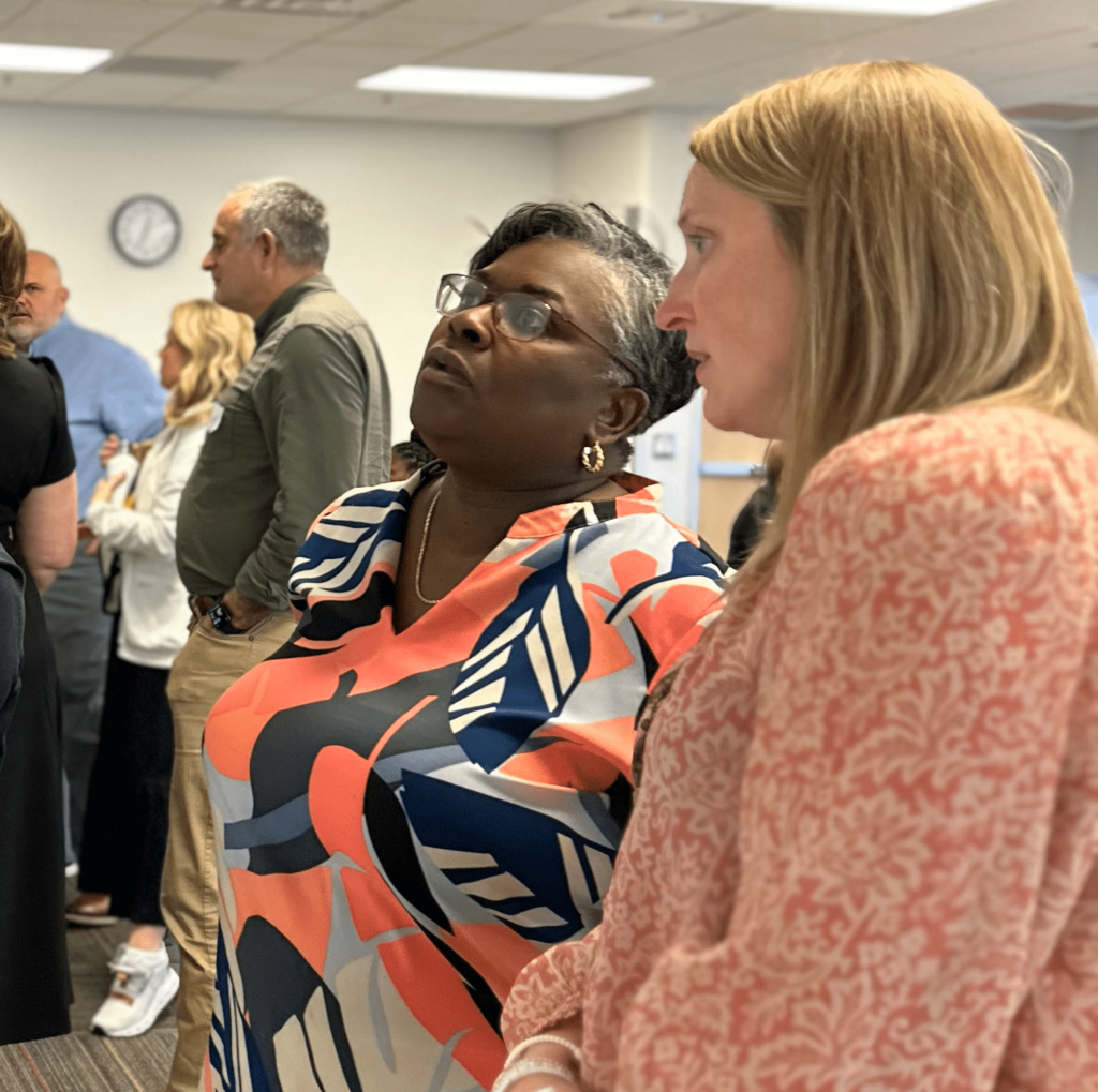 Educators place and move sticky notes on a white board