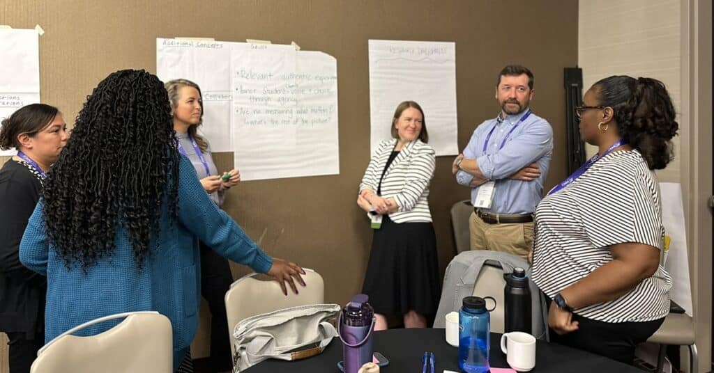A group of educators gather by posters on the wall for brainstorming